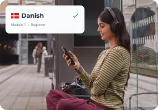 A learner sitting on a station platform, choosing Danish at Module 1 — Beginner in the Swap Language app