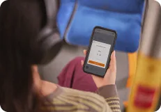 A learner on public transport practising on her phone, holding the microphone button to speak
